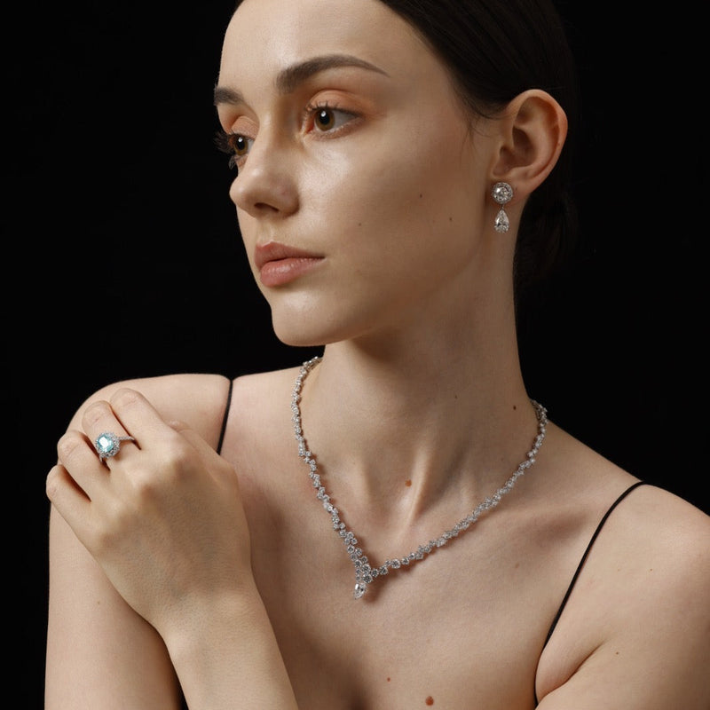 Woman wearing a diamond necklace and ring against a black background