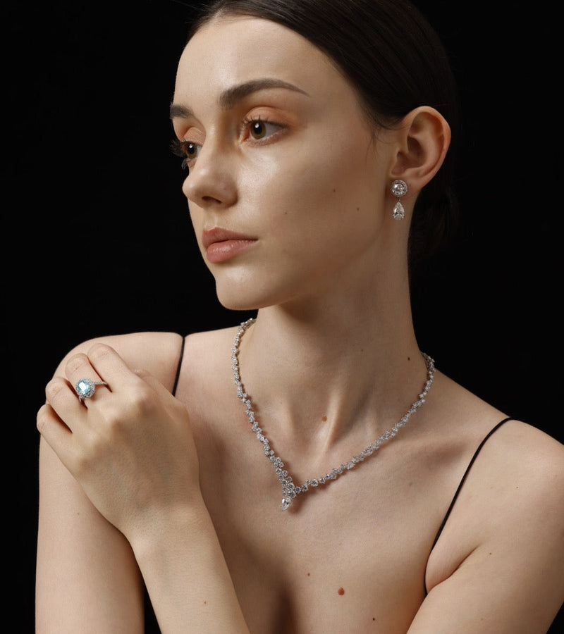 Woman wearing a diamond necklace and ring against a black background